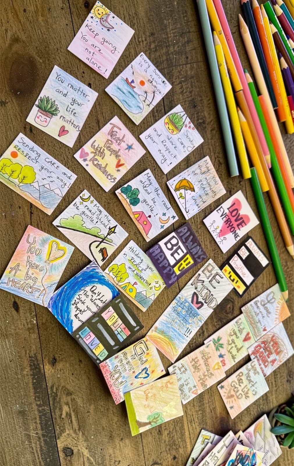 Hand-drawn cards laid out beside coloured pencils.