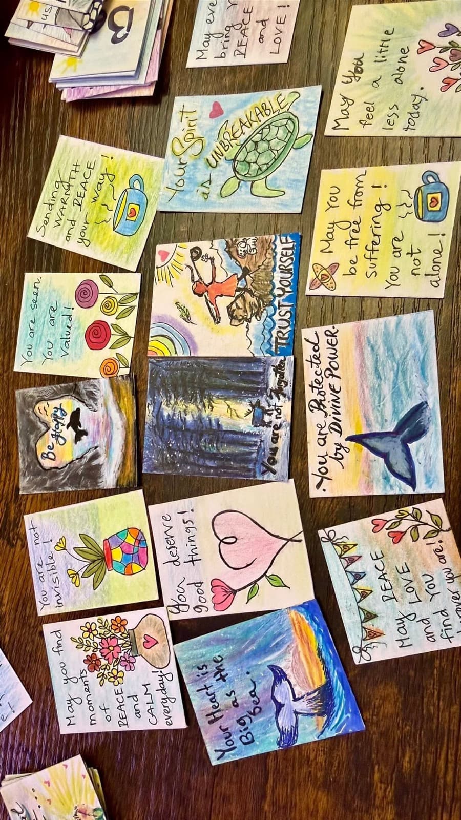 Hand-drawn cards carrying messages of peace, spread across a wooden table.